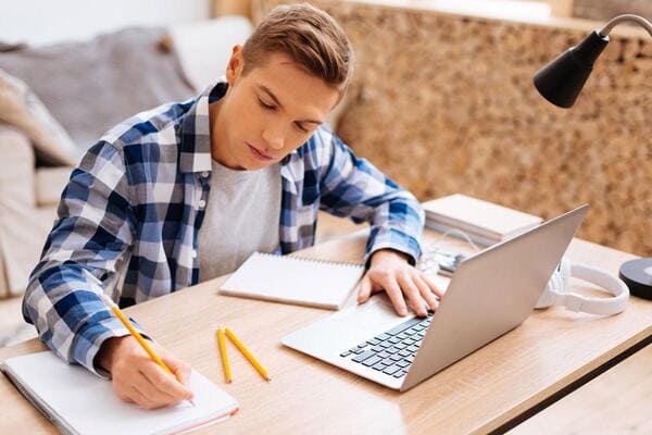 Pessoas a estudar numa mesa com cadernos e computador